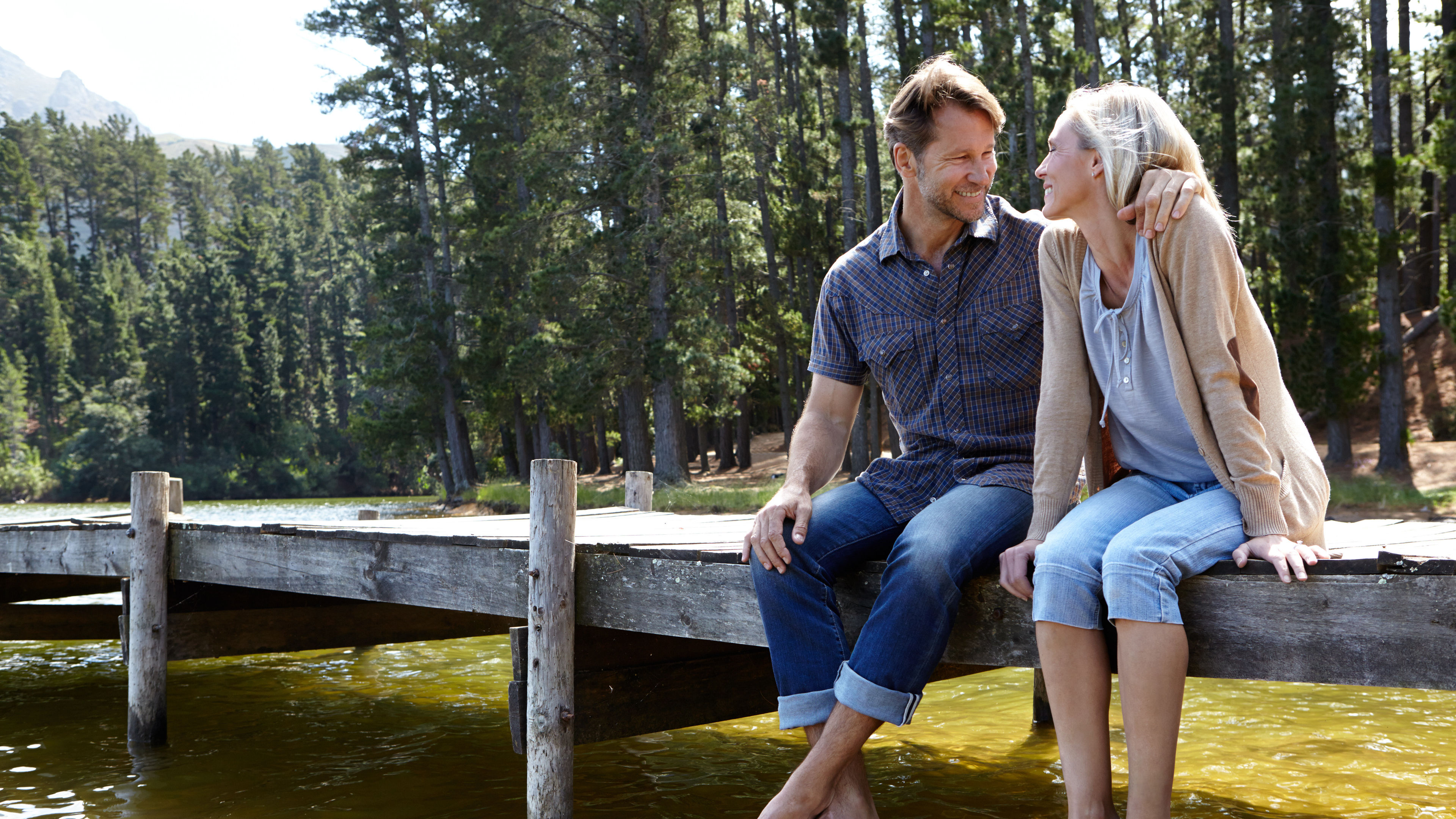 A couple sits near a quiet lake.
